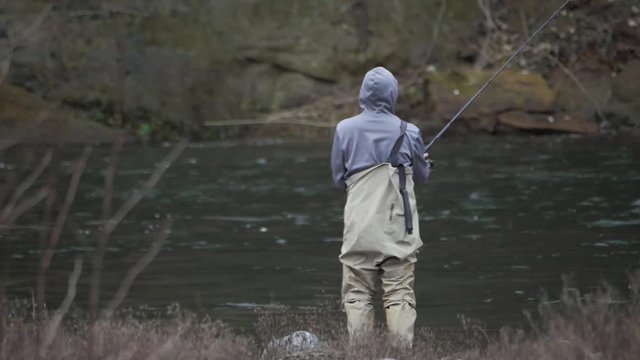 Male in waders alone fishing casting lure splashing on river water bank on sandy river in pacific northwest oregon in slow motion