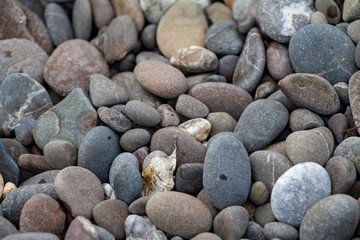 sea pebbles colored granite on the beach background stones. The shore of the beach with sand and pebbles washed by the waves of the sea.