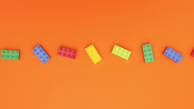 Looping colorful bricks toys moving on orange background - Stop motion