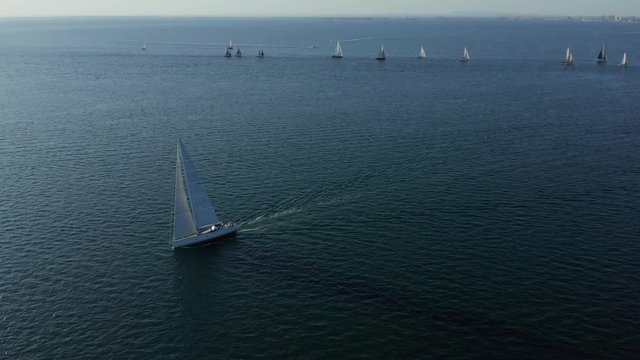 Aerial view orbiting yacht race under city skyline at sunset