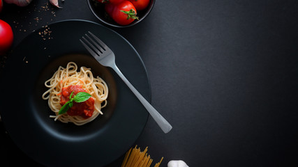 Top view of classic Italian spaghetti pasta with tomato sauce, ingredients and copy space