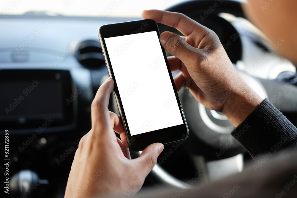 Poster Cropped shot view The driver uses the phone while driving. Modern smart phone with round edges. Isolated screen for mockup. Car navigation display in background. 