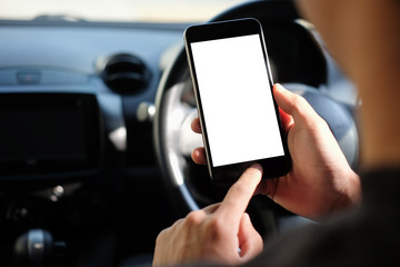 Cropped shot view The driver uses the phone while driving. Modern smart phone with round edges. Isolated screen for mockup. Car navigation display in background. 