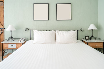 Bright and brand new interior of european bedroom with white lamp on wooden table and white blanket...