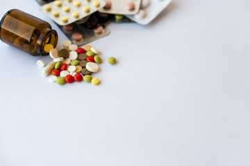 Medicine and pills. Multi-colored medicines on a white background close-up. Brown glass bucket and...