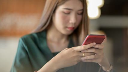 Close up view of female texting on smartphone in blurred simple office room background