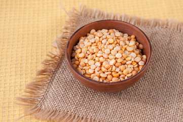 Pea groats in a clay Cup on a burlap table