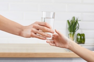 woman's hand gives a glass of purified water to her child. Concept purification of water
