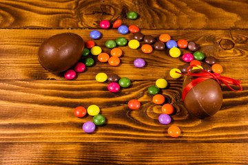 Chocolate easter eggs and multicolored candies on wooden table