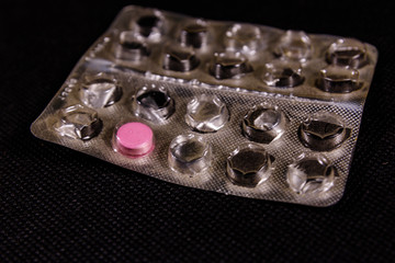 Last antibiotic pill in blister pack on a black background. Healthcare and medicine concept