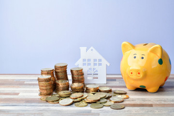 Close up of Wooden home, piggy bank and stack of money coins