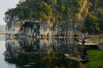 Fototapeta na wymiar Man fishing from dock with Water Moon Cave of Elephant Trunk Hill Park on Li River Guilin China