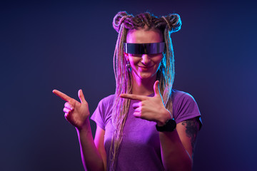 Happy woman with pigtails in sunglasses looking at camera in neon light