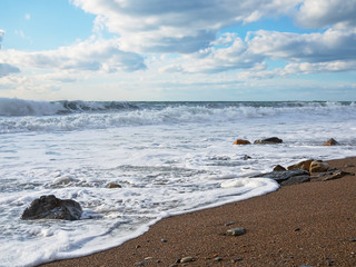 Sea beach with footprints on sand on background of blue sky and clouds. Nature background. Sea shore line on a black sea.