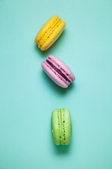 Green, pink and yellow macaroons on blue background.