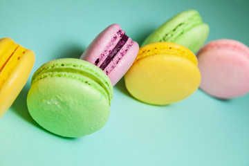 Different colorful macaroons on blue background.