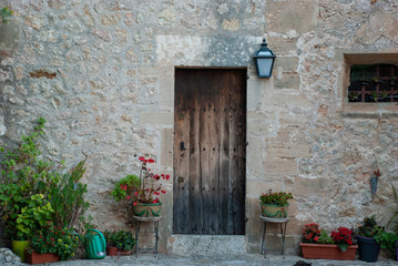 Fototapeta na wymiar Piktoresker Hintergrund eines spanisches Steinhauses mit Holztür und Blumen auf Mallorca