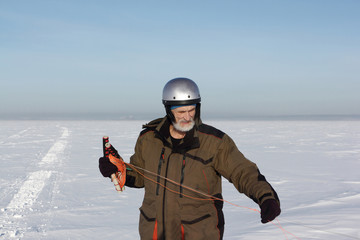 Fototapeta na wymiar Man unwinding slings at kite on snow, Ob reservoir, Novosibirsk, ,Russia