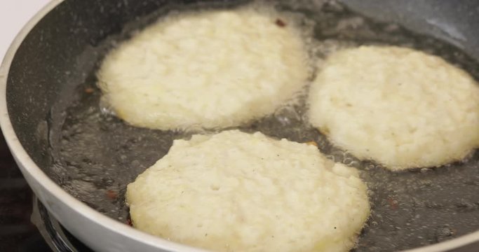Close-up chef cooking meat cutlets for burger in pan surrounded by boiling oil 4k footage. Male hands in gloves preparing unhealthy fat food at kitchen working at restaurant or cafe