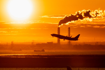 朝日を浴びて離陸するジェット旅客機