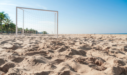 Soccer goal post on the beach with sand and blue sky
