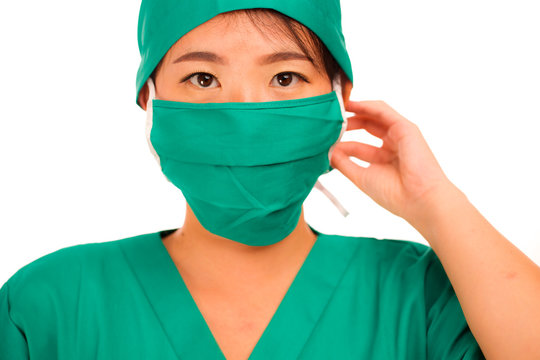 Isolated Portrait Of Young Beautiful And Serious Asian Chinese Medicine Doctor Woman Or Hospital Nurse In Medical Hat Surgeon Face Mask And Green Scrub In Successful Health Care