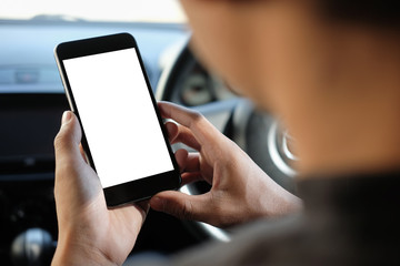 Cropped shot view The driver uses the phone while driving. Modern smart phone with round edges. Isolated screen for mockup. Car navigation display in background. 