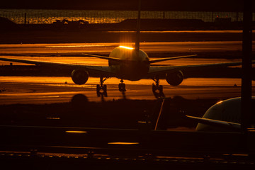 夜明けに朝日を浴びてタキシングするジェット旅客機