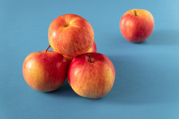 A few juicy ripe yellow-red apples are stacked with a bunch on a blue background. Copy space.