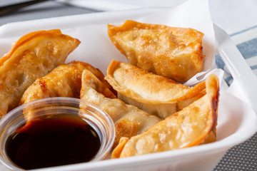 A container full of freshly made gyoza in a restaurant or kitchen setting.