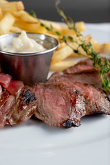 A closeup view of a plate of steak and frites, in a restaurant or kitchen setting.