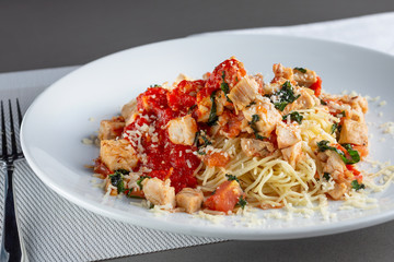A view of a plate of chicken angel hair pasta in a restaurant or kitchen setting.