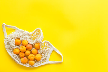 Textile eco bag with fruits on yellow background top-down copy space