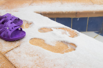 Winter swimming in a warm thermal spring. Purple slippers and footprints in the snow in front of a pool of warm water in the open air.