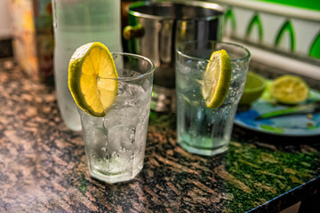 Alcoholic homemade drink (tonic cocktail tonic) with lemon and ice on marble table.