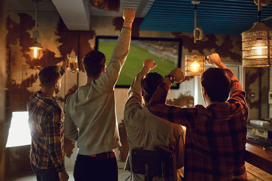 A group of friends watching tv football in a sports bar.