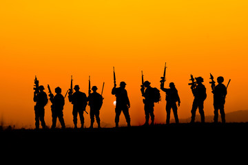 silhouette of Soldier team backdrop of sunset sky.Soldier with machine gun patrolling 