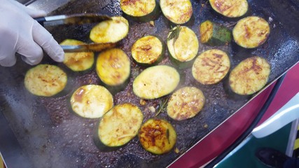 Roasting zucchini slices on a stove.
