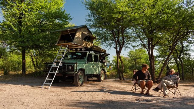 Timelapse of adventurous couple on camping (self-drive) Safari in Botswana (Game Reserve/Park), with camp truck and tent, having coffee and packing up camp.