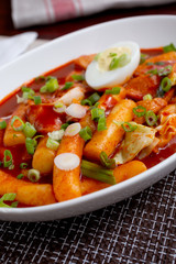 A view of a plate of Korean Tteok-bokki, which is a spicy rice cake dish, in a restaurant or kitchen setting.