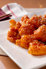 A plate of Chinese orange shrimp in a restaurant or kitchen setting.