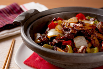 A plate of spicy beef in a stone serving pot in a restaurant or kitchen setting.
