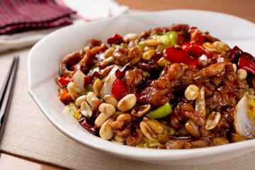 A view of a plate of kung pao chicken in a restaurant or kitchen setting.