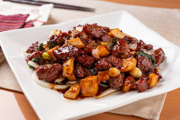 A plate of garlic beef cube in restaurant or kitchen setting.