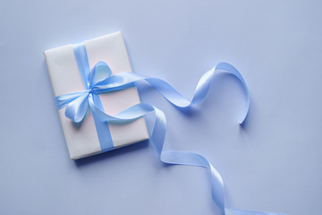 Decorative white gift box with blue bow and long beautiful ribbon. Top view