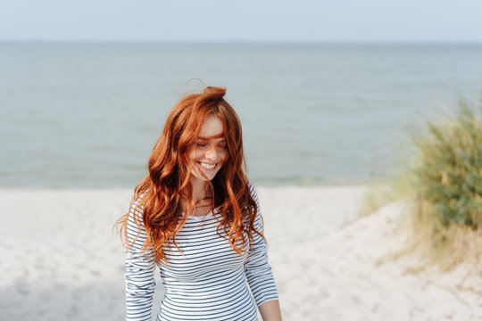 Happy young redhead woman smiling to herself