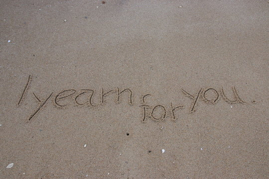 Handwriting  words "I yearn for you." on sand of beach.