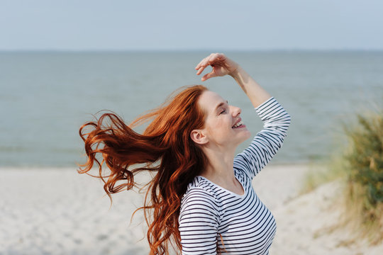 Carefree young woman tossing her long red hair