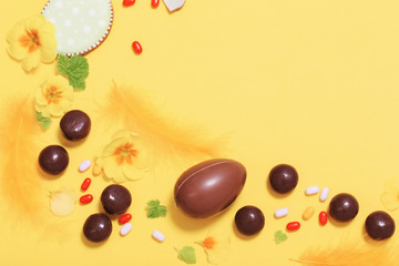 Easter yellow background with chocolatte eggs,    candy and spring flowers