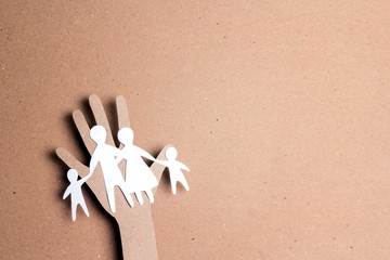 Paper cut family silhouette in a cardboard hand.